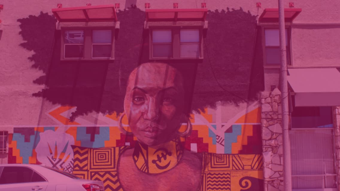 Mural of a Black woman with an afro framed by the windows of a Long Beach building